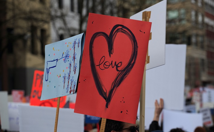 Red protest sign with heart and word "love" in it