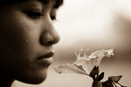 All Saints image of woman crying while looking at flower