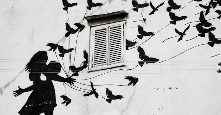 Mural of silhouette girl reaching out; birds flying upward