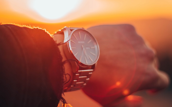 man wearing wristwatch in front of sunset