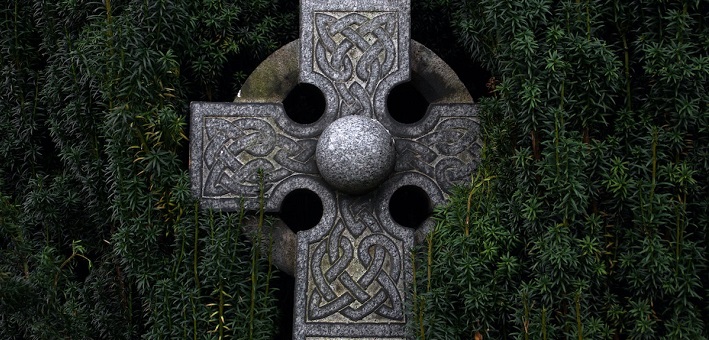 Celtic cross surrounded by evergreens