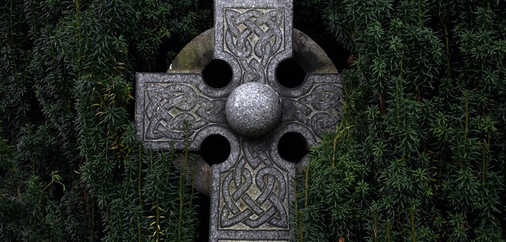 Celtic cross surrounded by evergreens