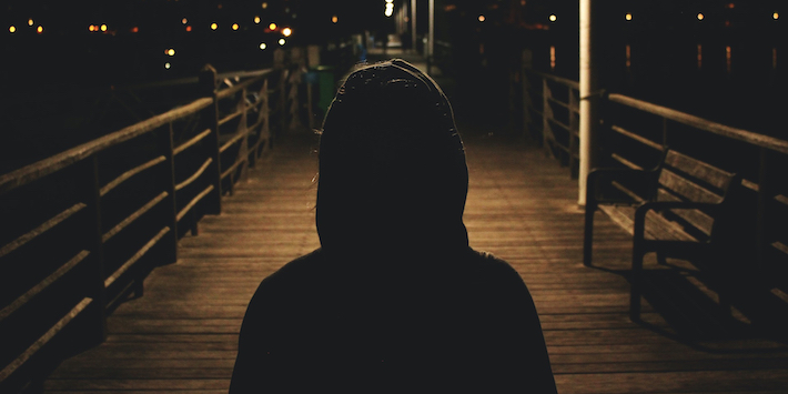 hooded figure alone on boardwalk