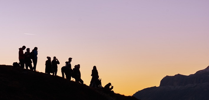 Silhouetted figures on hill at sunset