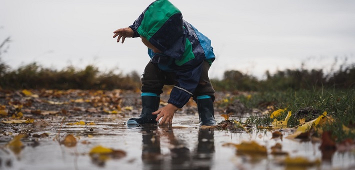 Toddler reaching hand into puddle