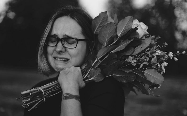 woman crying outside with flowers in hand