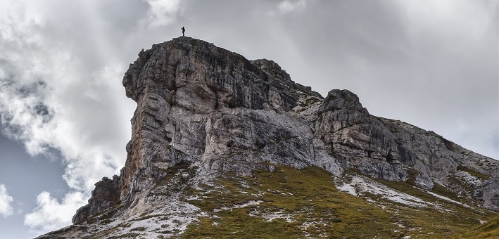 figure standing on mountaintop with white clouds behind