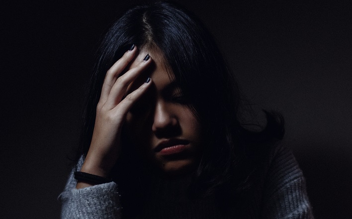 Woman holding her head in darkness