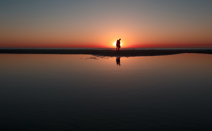 Two figures walking on lakshore at sunset