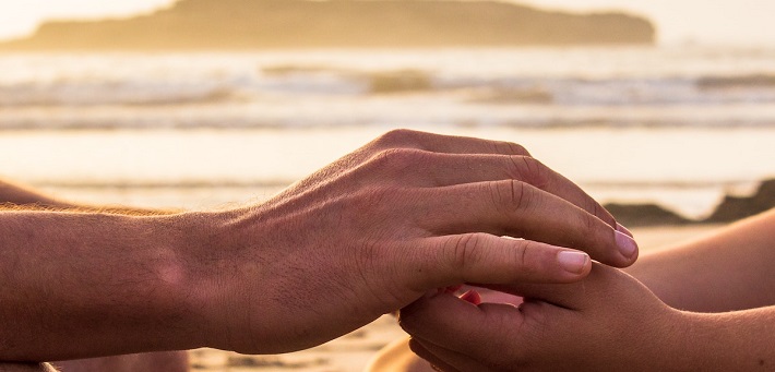 hands interlocked in front of beach