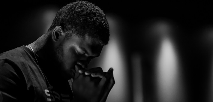 Man praying in dimly lit room