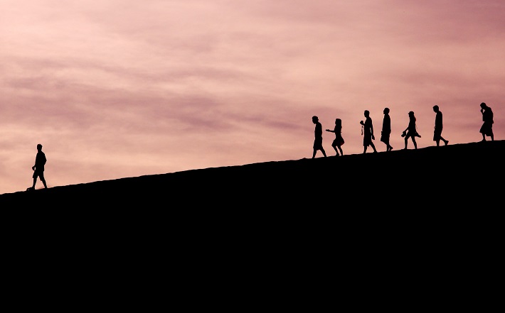 silhouette of person walking in front of group of people