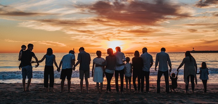 Group of people standing on beach watching sunset