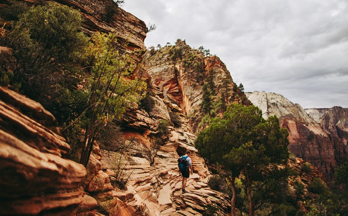 Man hiking up difficult slope under clouds