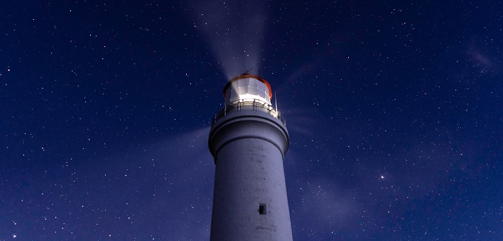 lighthouse shining against deep blue sky