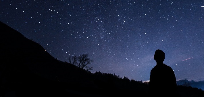 silhouetted figure looking up at stars