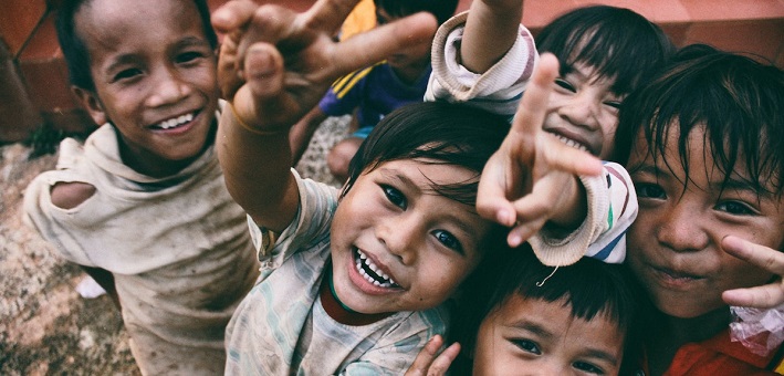 Children smiling and making peace signs with their hands.