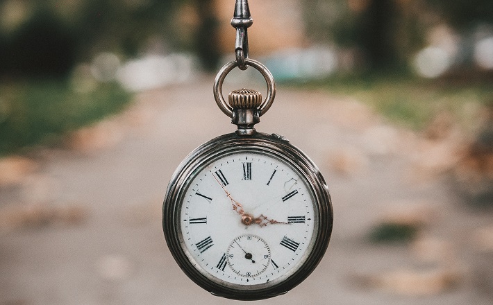 pocketwatch hanging in front of leaf-strewn walk