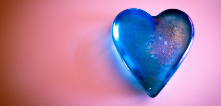 Blue glass heart on pink background