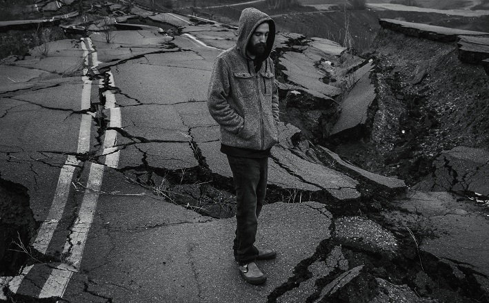 Man standing on shattered highway after earthquake