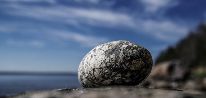 a stand alone rock near a body of water