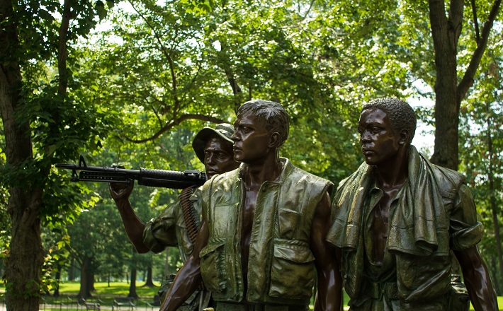 Statue of three soldiers with green leafy backdrop