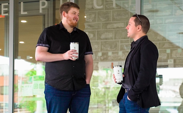 Two men talking over coffee in front of glass wall