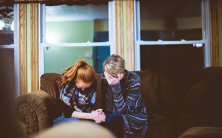 Women consoling one another at table