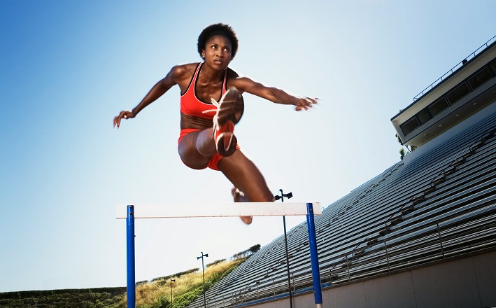 Woman demonstrating agility by hurdling on track