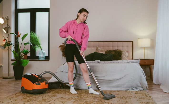 Teen doing chores (vacuuming the living room in apartment)