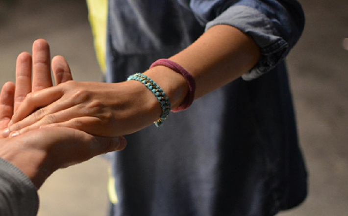 Woman reaching out to touch hand of another