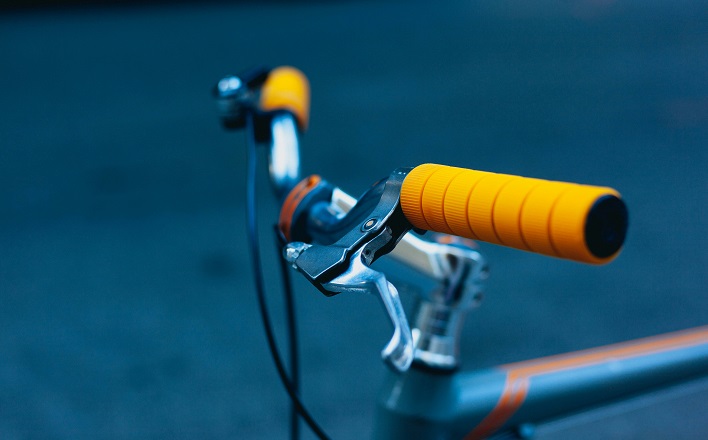 bicycle handlebars with orange grips. (Theme: Why do we bless bikes?)