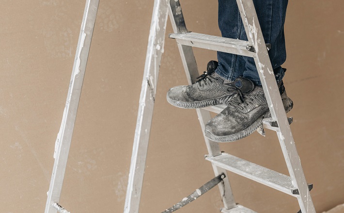 Feet of man standing on ladder.
