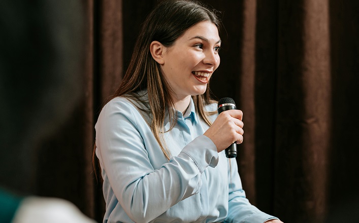 Lay preacher (young woman) in front of curtain