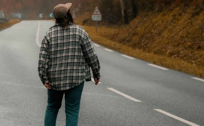 Figure walking down highway looking up the hill