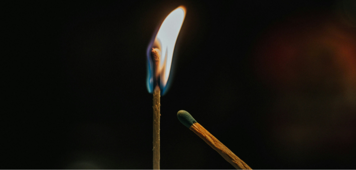 Photo of one match lighting another in the dark