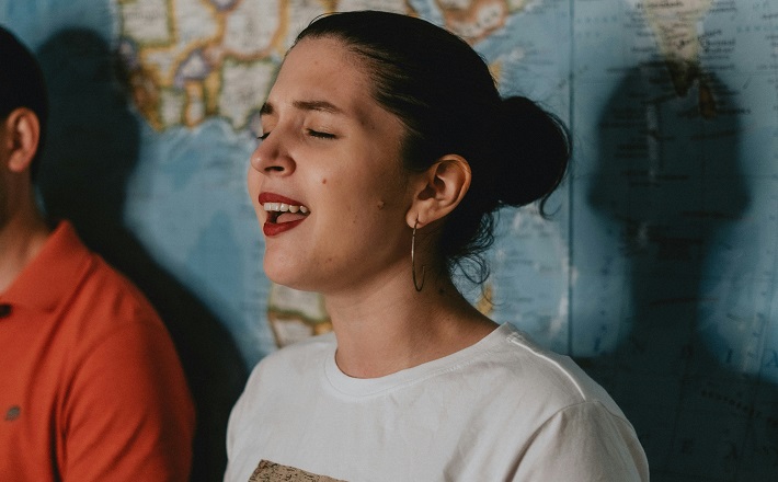 Woman sings in front of world map
