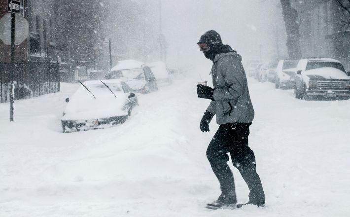Man crossing street in urban area after snowstorm.