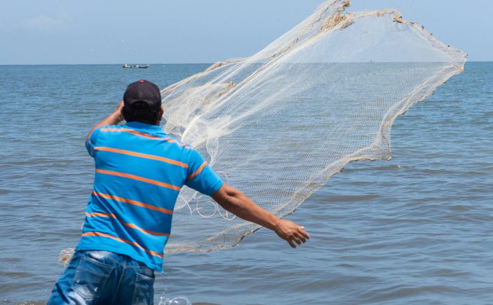Man casting net into the sea