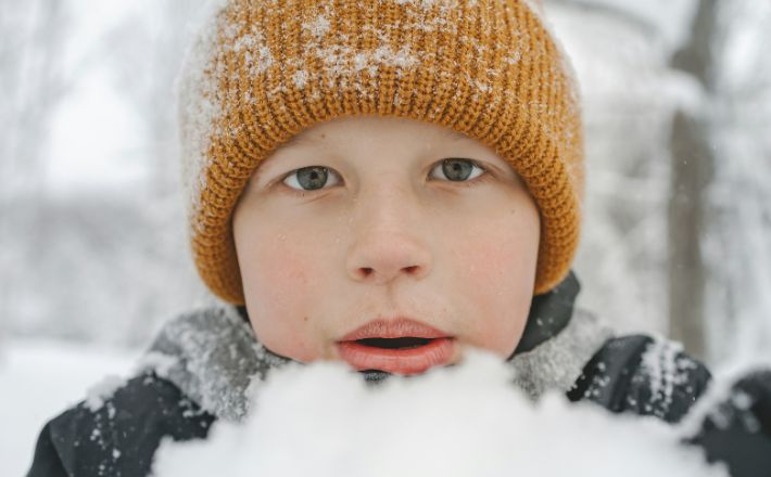 Boy with winter hat in front of snow