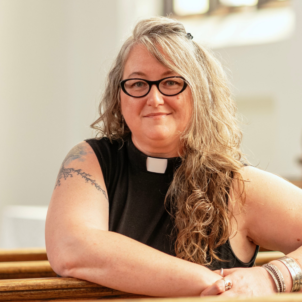 Rev. Leah Robberts-Mosser turning to the back of a pew for a photo.