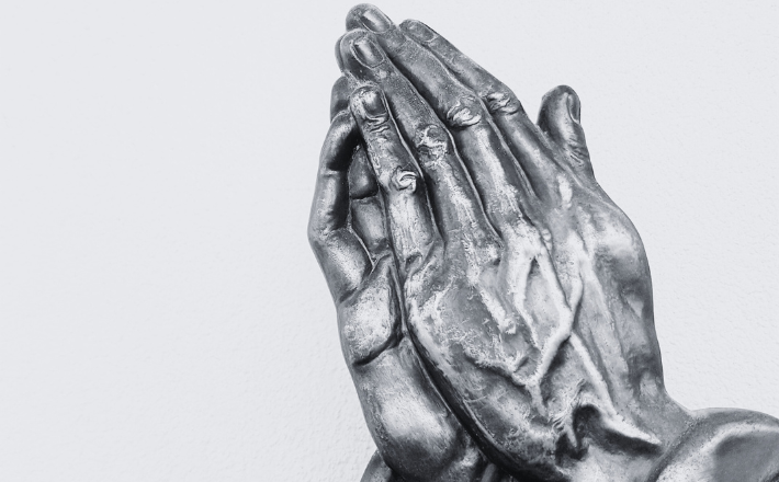black and white photo of a praying hands statue