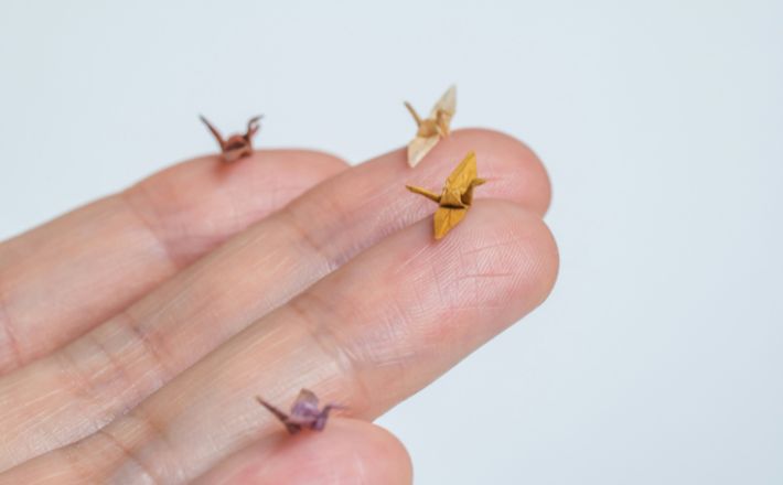 Hand holding four tiny origami birds