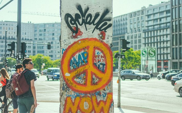 Piece of Berlin Wall with peace sign and the word Now in graffiti