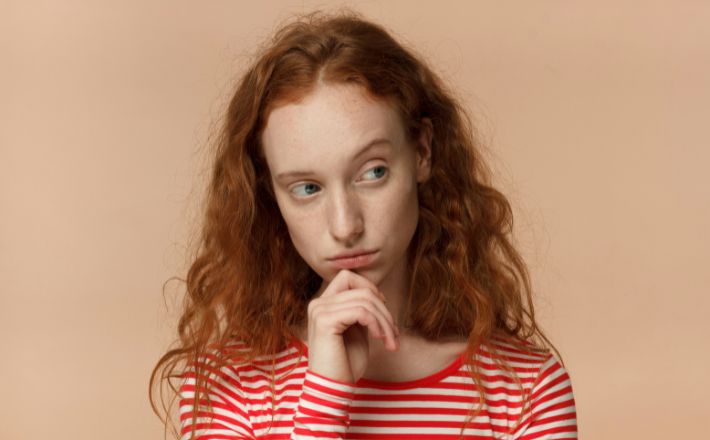 Woman in red-striped shirt looking skeptically to the right