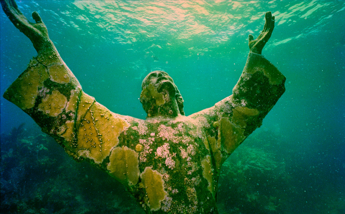 photo of an underwater statue of Jesus with arms outstretched