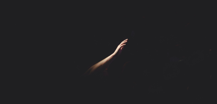 photo of a lighted arm coming out of darkness
