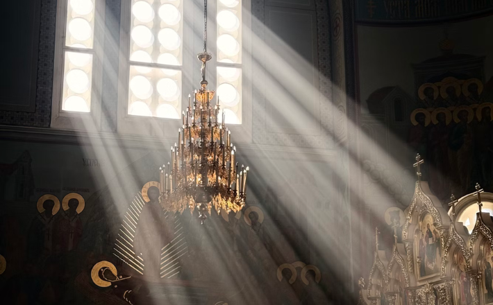 Sunbeams stream through church windows illuminating chandelier