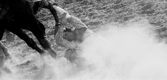 black and white photo of a man being dragged by a horse