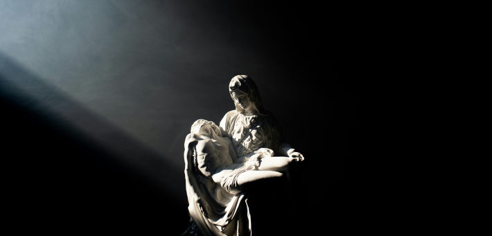 photo of a pieta statue illuminated by sunbeam